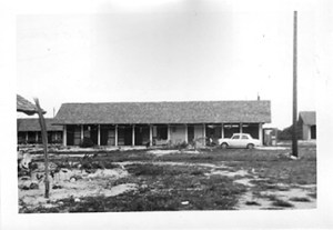 The packing crate is at the end of the house on the right side.